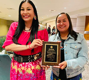 two women holding an award
