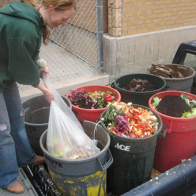 student dumping a bucket of compost into truck bed