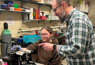 student and professor at microscope