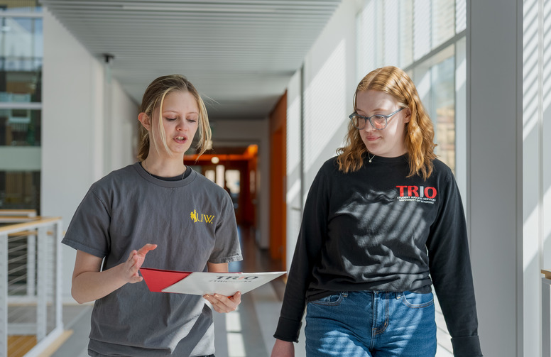 Two students in dark shirts walk together talking.