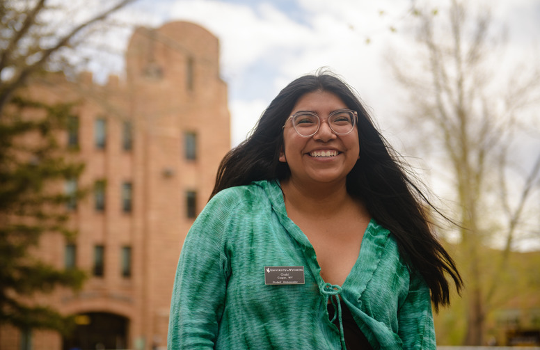 A student stands in front of the the Wyoming Union in a green shirt.