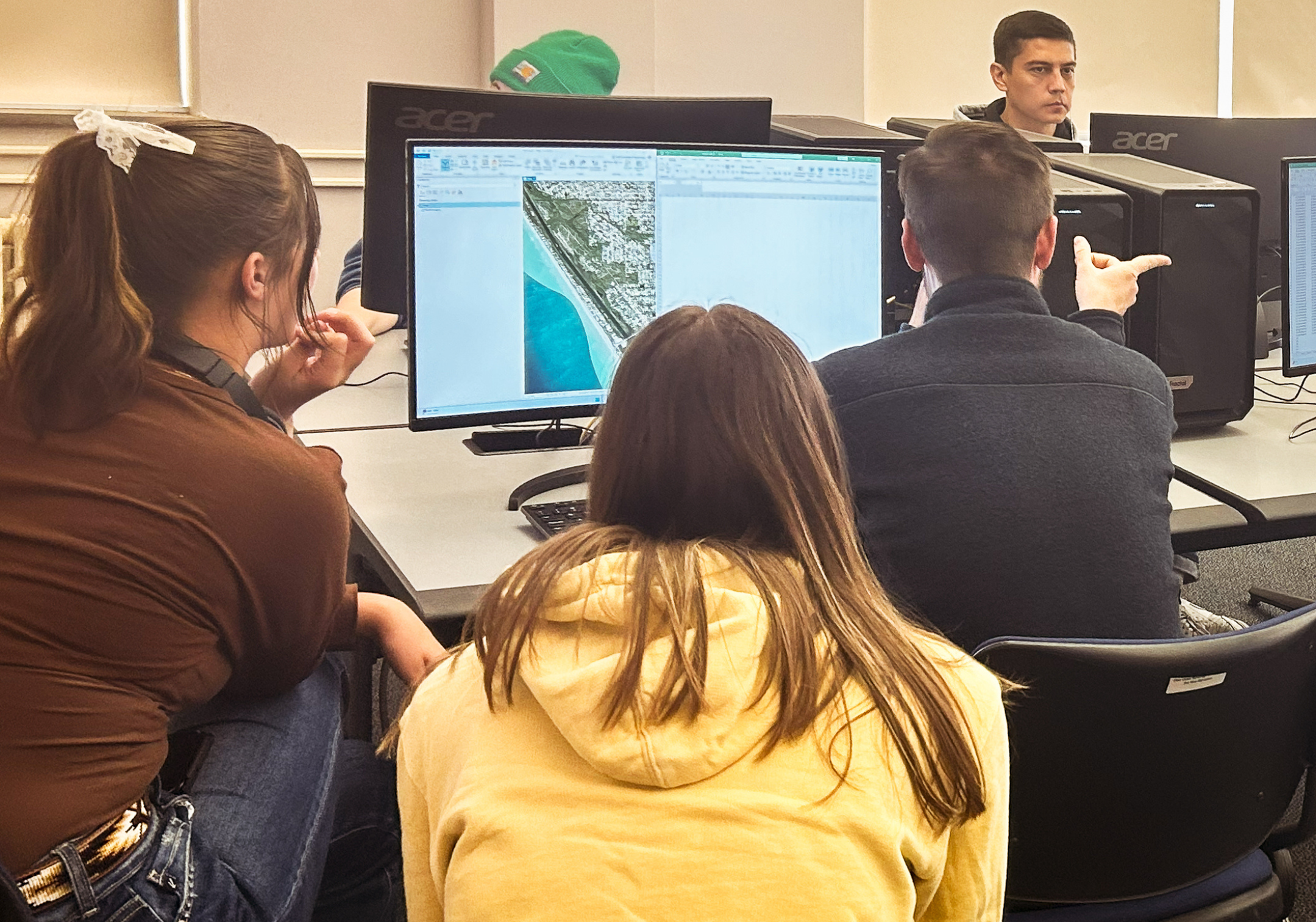 Taryn Day and Samantha Bemis (both biology majors) listen as Jack Alford describes the types of damages that can be interpreted from aerial images. Photo by Tom Musselman.
