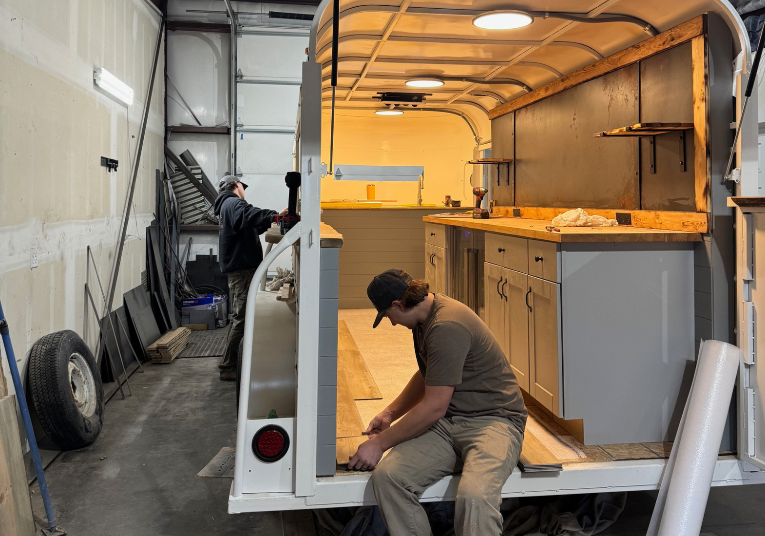 Cody Korsmeyer installs flooring in a beverage trailer during the final stages of construction. Photo by Lacey Korsmeyer.