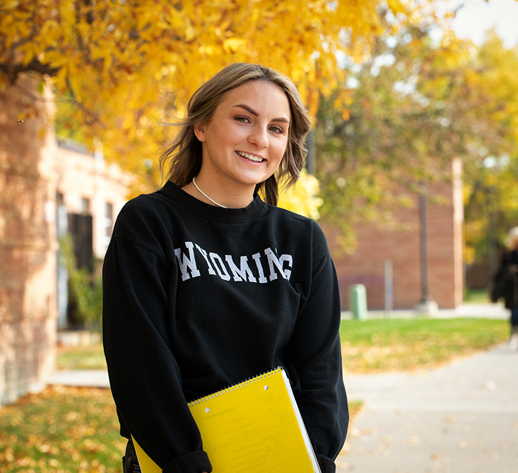 Student standing in front of fall colors outside