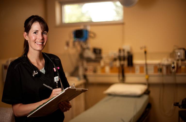 Health Leadership student writes on a clipboard