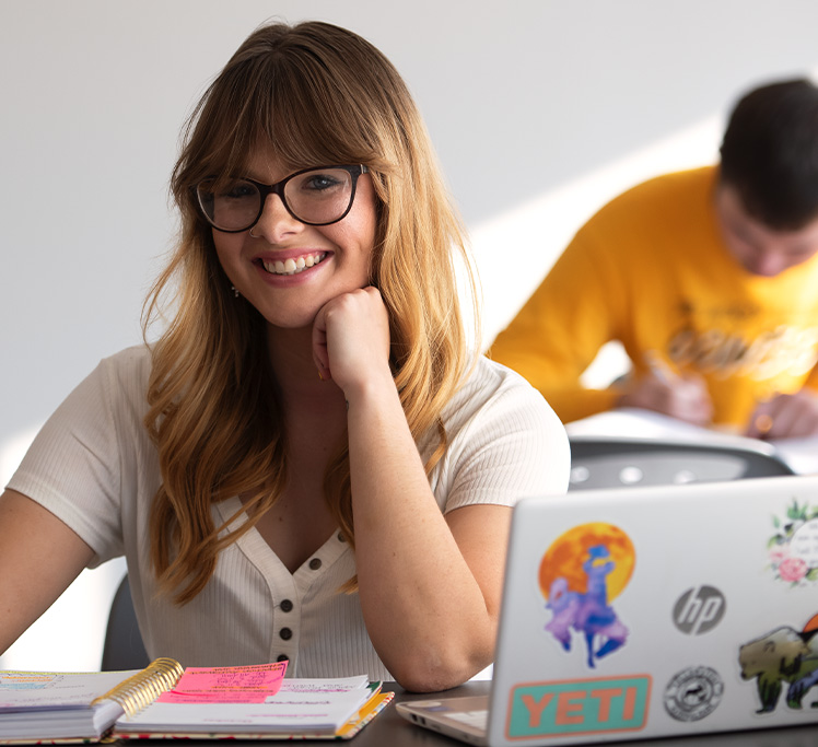 Student smiling by computer