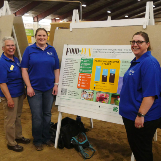a group of people smiles while standing around a poster