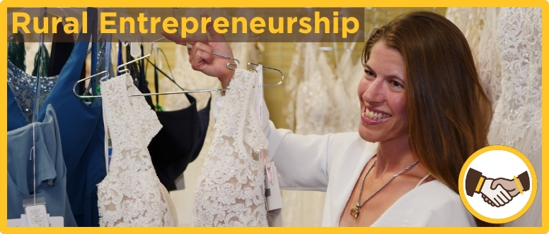 a woman holds up a wedding dress on a hanger