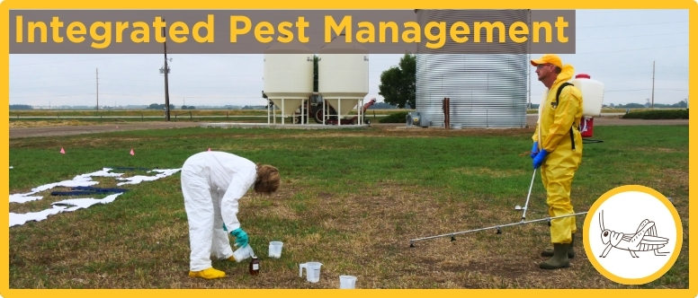 2 people dressed in chemical resistance suites calibrate a boom sprayer in a field