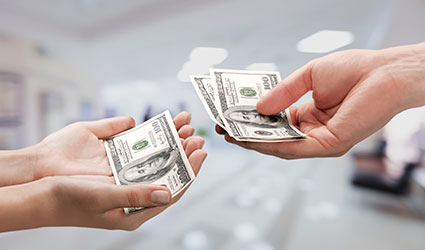 dollars bills being handed between two people where we only see the hands
