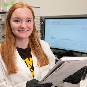 researcher at computer holding notebook