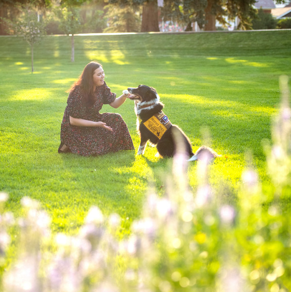 Person sitting with their dog in grass. 