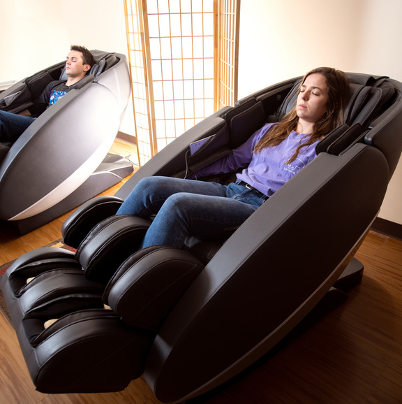 Two people sitting in massage chair.