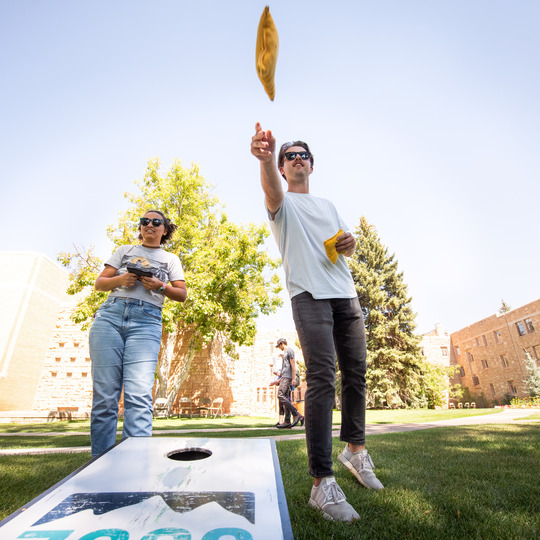 Two people playing cornhole.