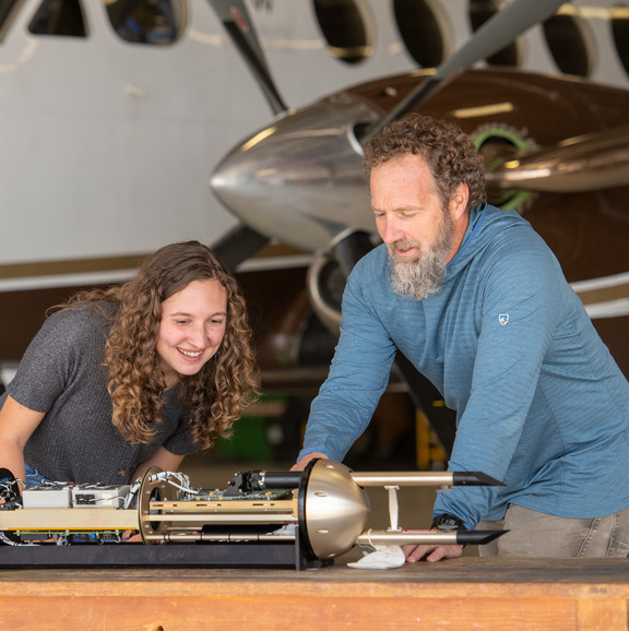 two people look at an airplane part