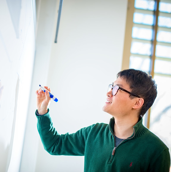 student writing on a white board