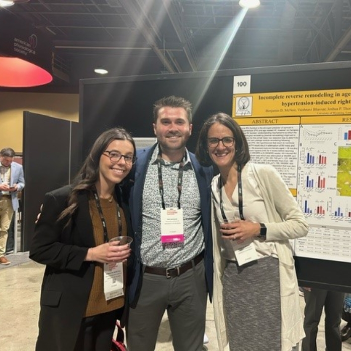 Three people at a conference smiling for a picture