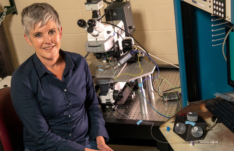A faculty member smiles for the camera at their lab station