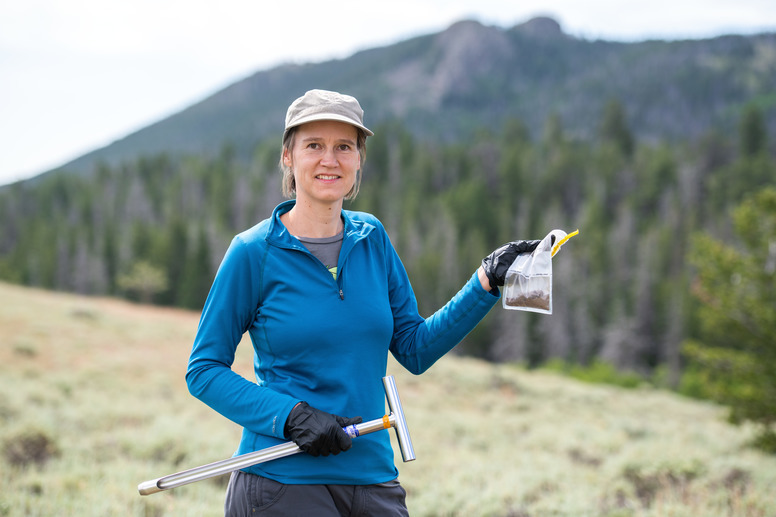 A professor holds a bag out in the field