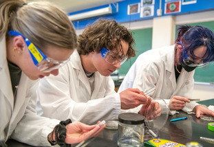 students in lab coats working with lab tools