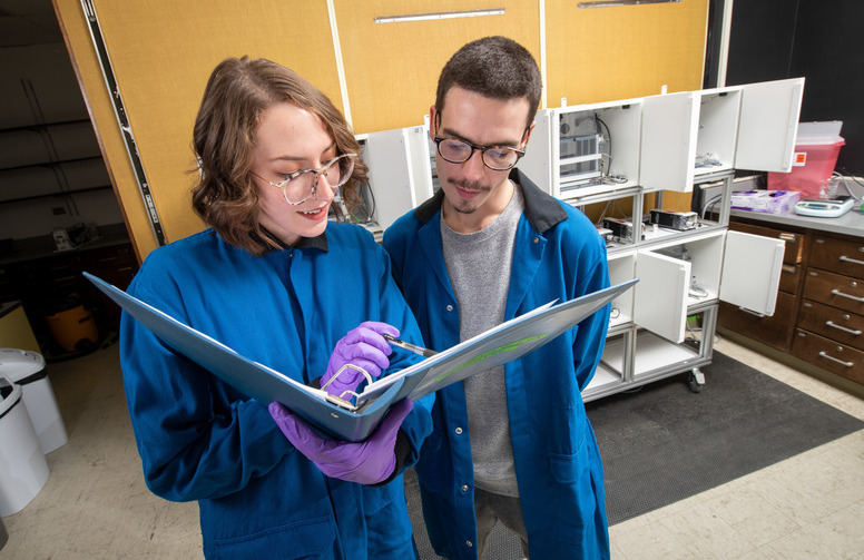 Two students examine a lab book together during lab