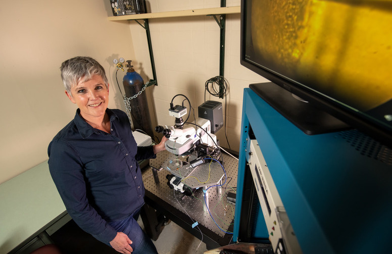 A professor stands in their lab smiling for a picture
