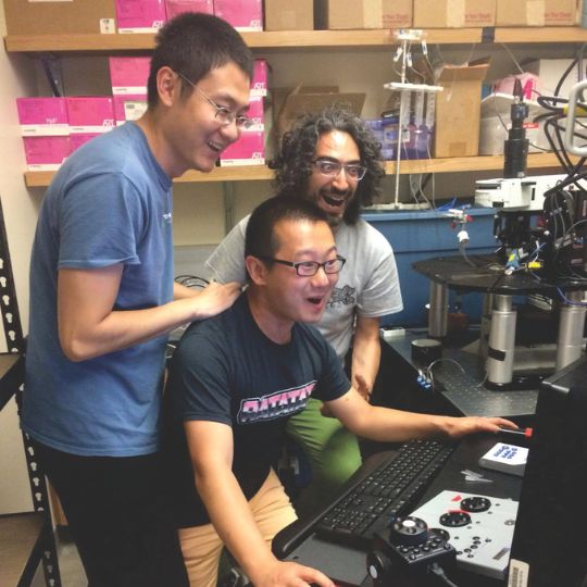 Three students look at a computer together during a lab