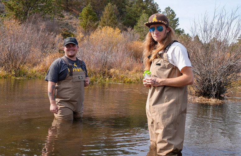 Two students stand in a body of water