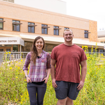 Two students stand and smile for a photo