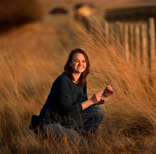 A student smiles for a photo out in the field