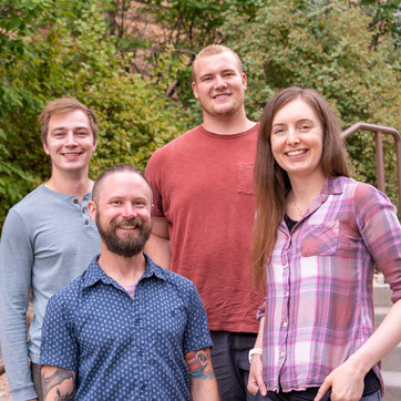 A group of four students and faculty members smile for a photo