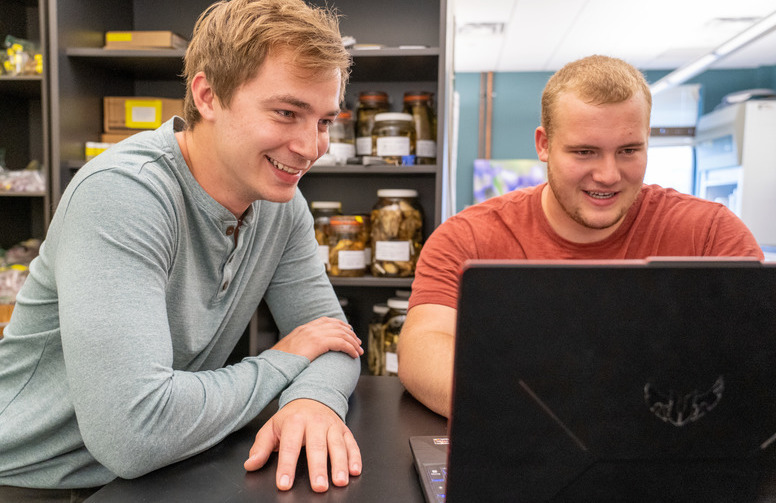 Two students look at a laptop together during a lab