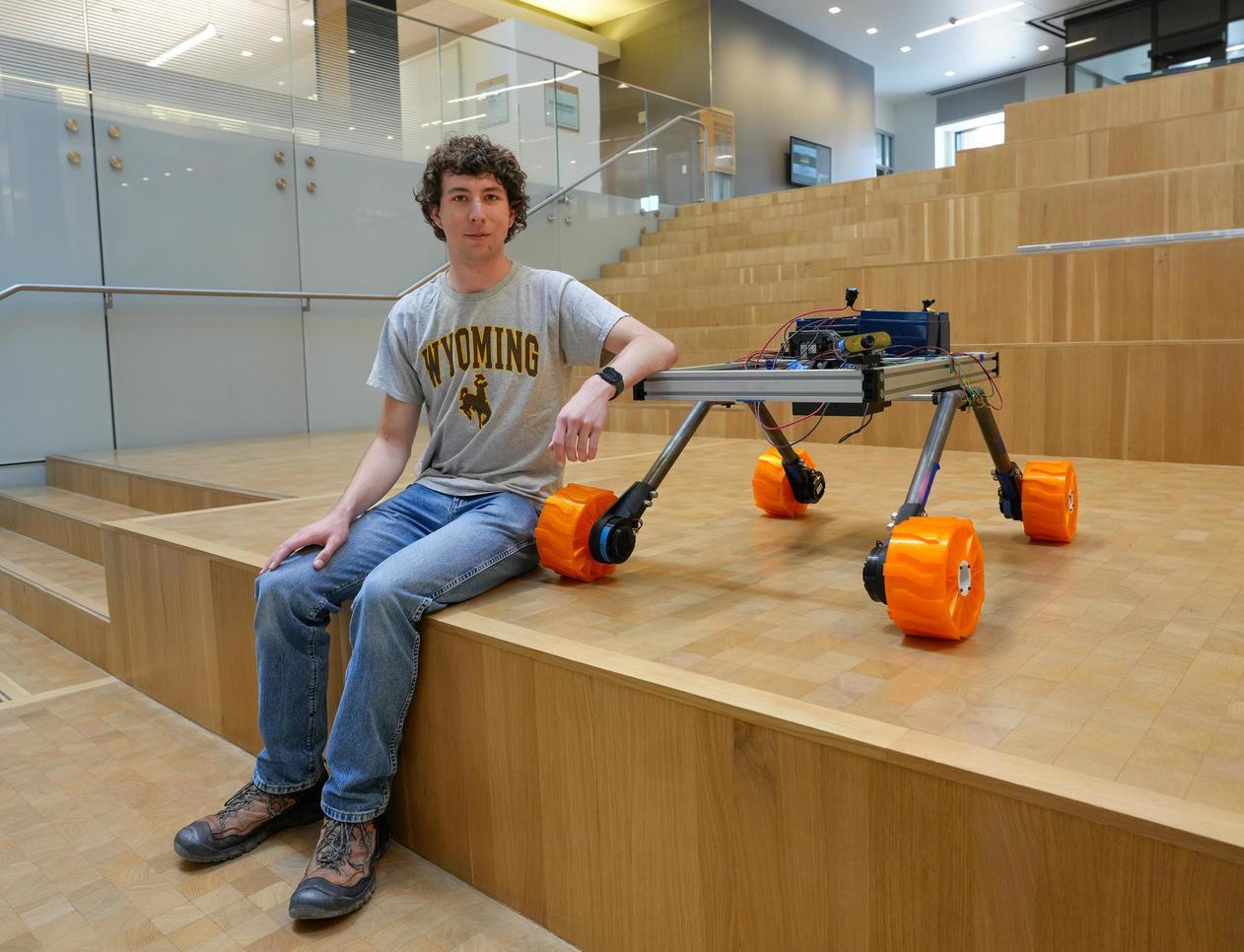 A student sits on some steps with his robot