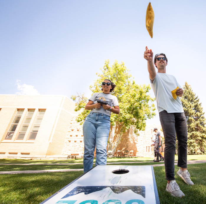 Students playing cornhole at Graduate School picnic