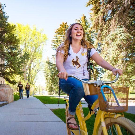 Person riding bike near old main building.