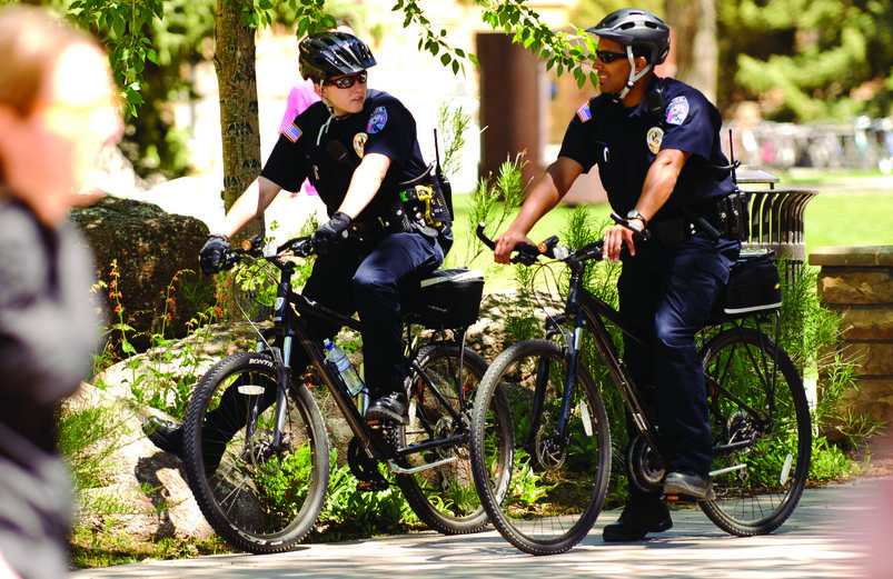 Two UWPD officers ride bikes on UW’s campus as part of their campus police duties