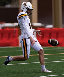 football player kicking the ball on the football field