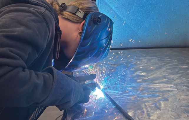female student works a welder
