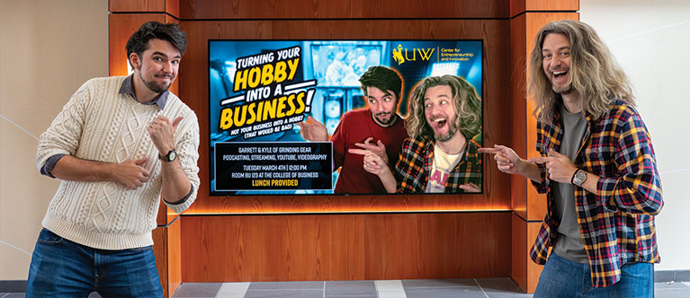 two men pointing at a screen advertising their speech