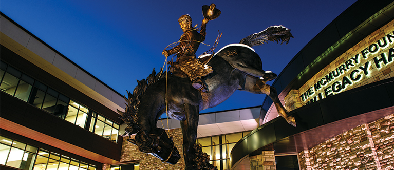 statue of horse and rider in front of Gateway Center at night