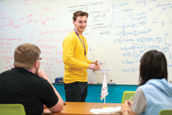 Two students and a student tutor looking at a whiteboard