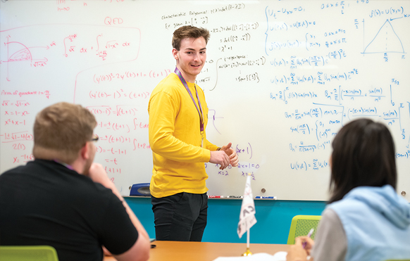 Two students and a student tutor looking at a whiteboard