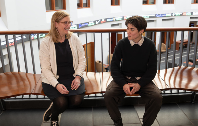 Staff member and student sit in the College of Business atrium