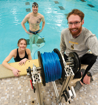 two mechanical engineering students and a swimmer worked in the pool with their resistance training equipment