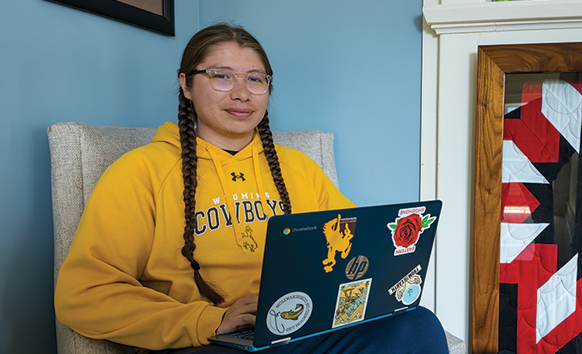 Student sitting in a chair with a laptop in the Native American Education, Research and Cultural Center
