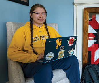 Student sitting in a chair with a laptop in the Native American Education, Research and Cultural Center