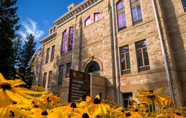 Exterior of Old Main with black eyed Susan flowers in front