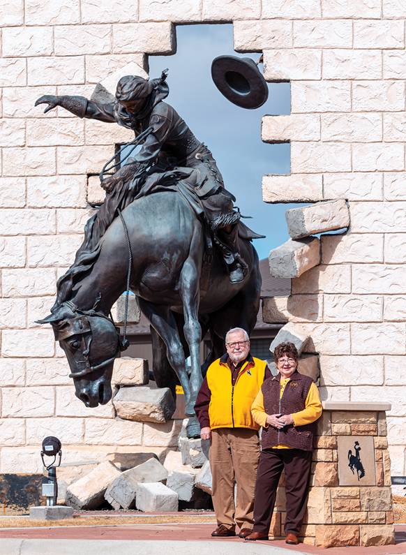 couple in front of large statue of a woman riding a horse