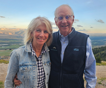 two people pose outside with mountains in the background