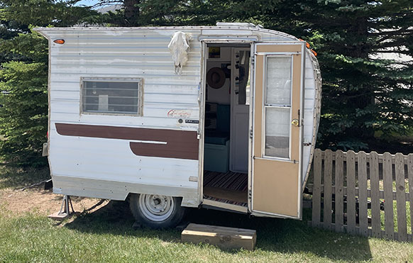camper with door open outside by a fence